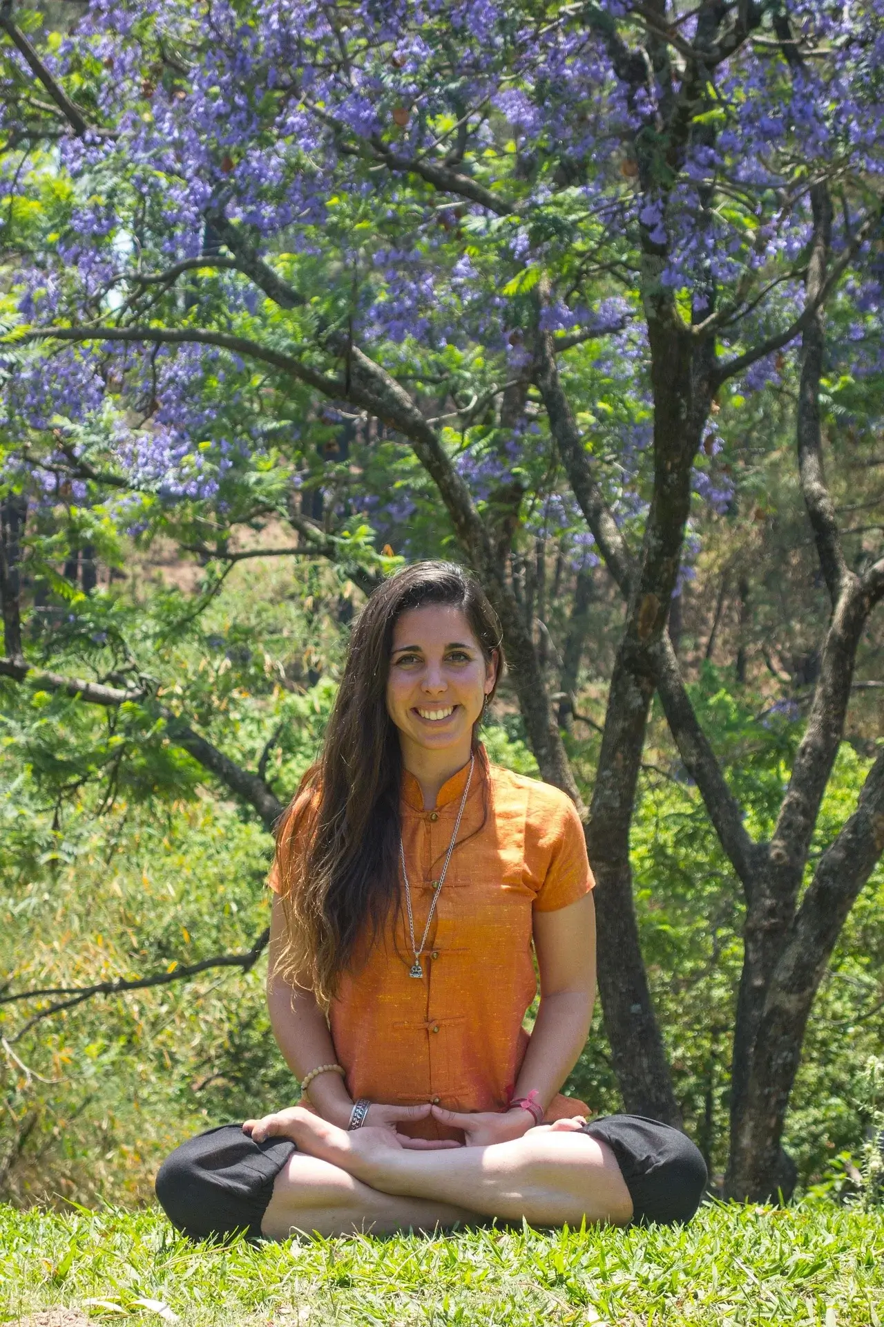 A woman meditates outdoors under purple flowering trees, inviting questions about addiction or rehab for those seeking treatment options in Missouri.