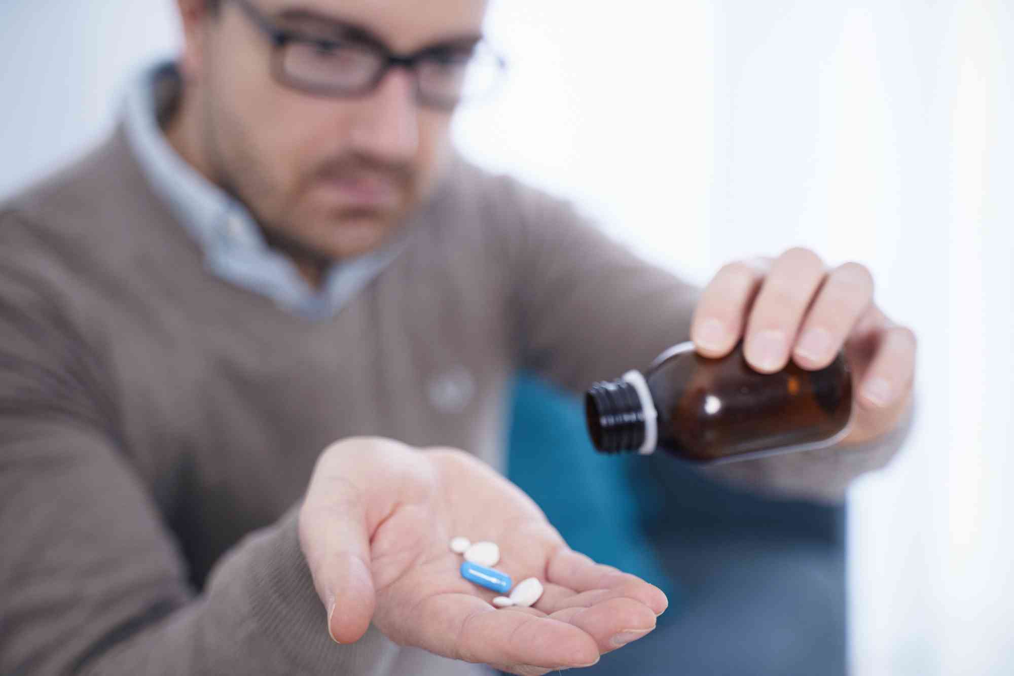 Man pouring multiple prescription pills into his hand, illustrating benzodiazepine misuse.