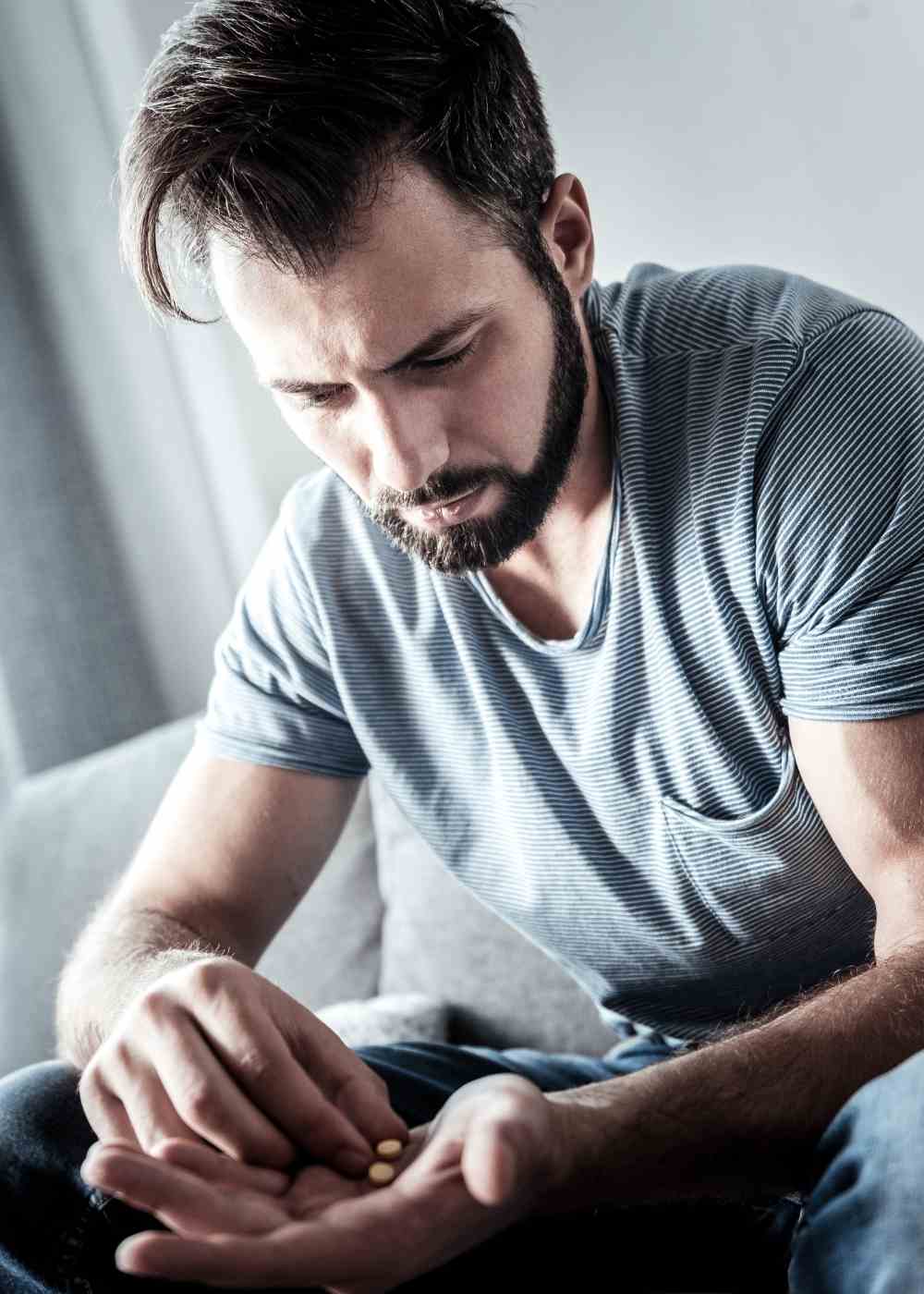 Man holding pills in his hand showing Adderall misuse and stimulant addiction