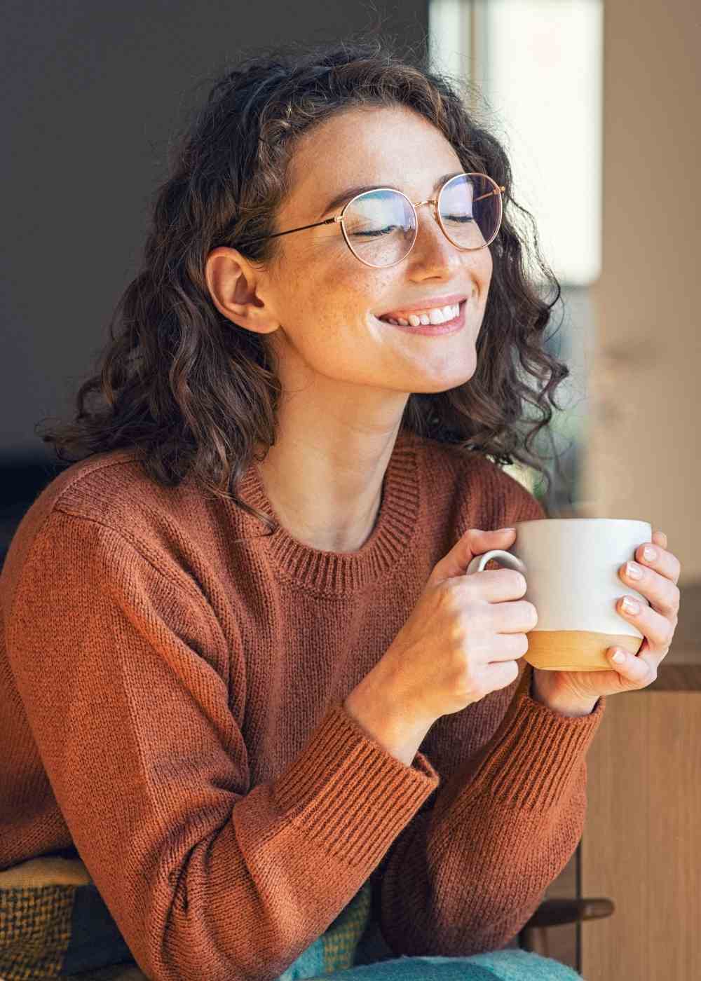 Woman smiling peacefully holding a cup showing recovery and emotional healing