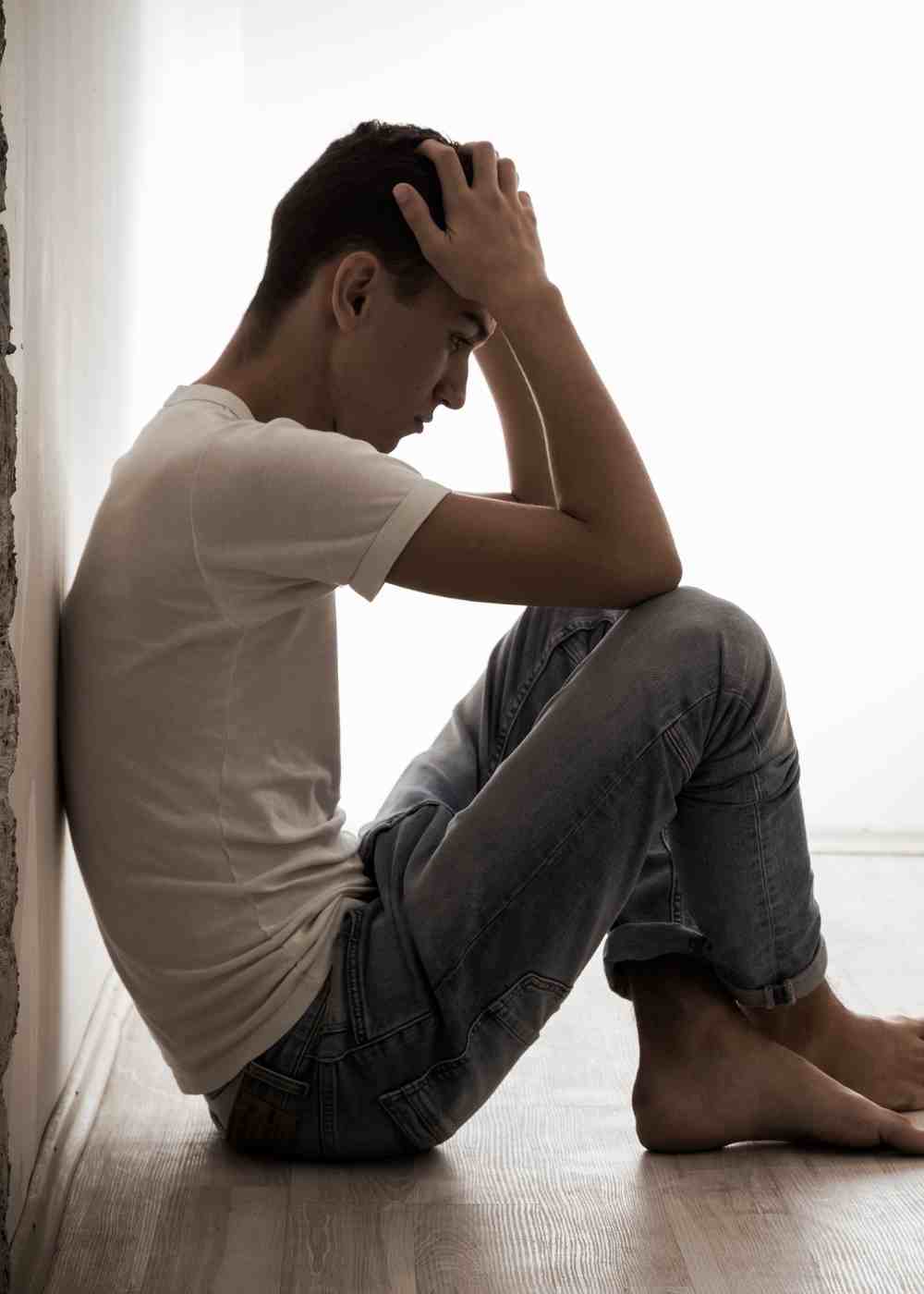 Man sitting on floor holding head showing anxiety and Xanax withdrawal symptoms