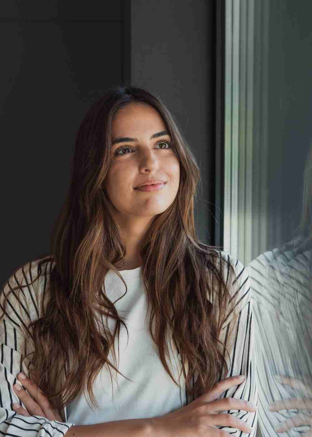 Woman looking out a window with hope during cocaine addiction recovery after treatment